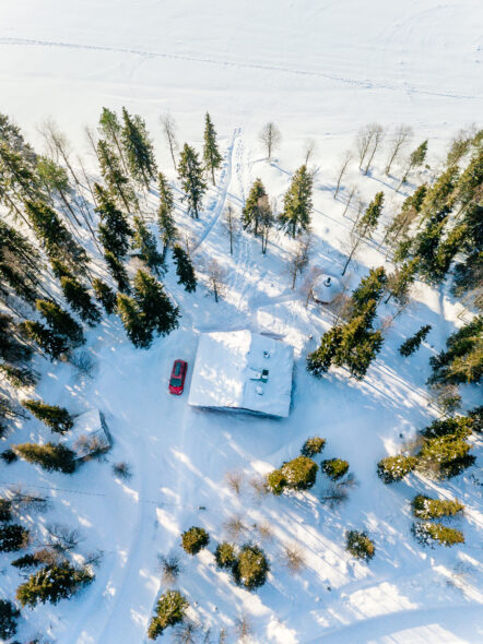 Aerial view of wooden log cabin in snow  winter forest by the lake in rural Finland